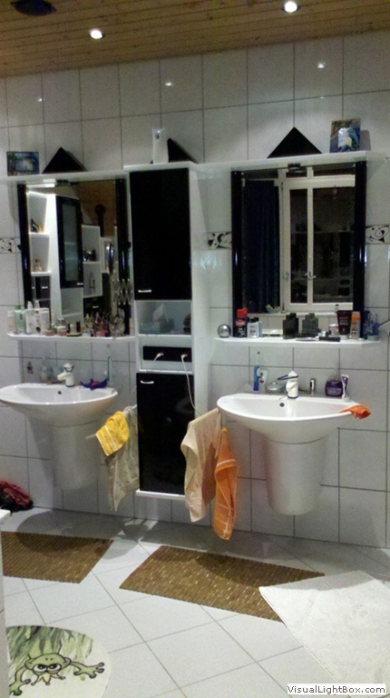 Badezimmer mit zwei Waschbecken, Spiegeln und einem schmalen schwarz-weißen Schrank.