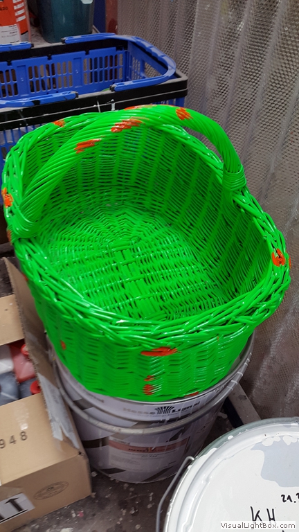 Leuchtend grüner Flechtkorb mit Henkel in einer Werkstatt.