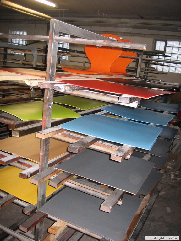 Orangefarbene, blaue und dunkle Sitzschalen auf einem mehrstöckigen Gestell.