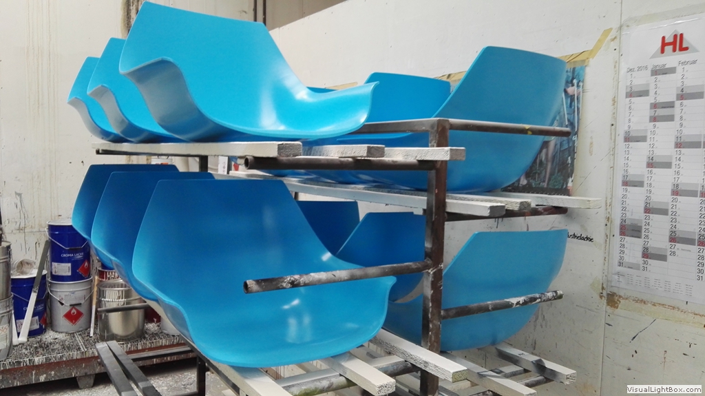 Türkisfarbene Sitzschalen auf einem mehrstöckigen Metallgestell.