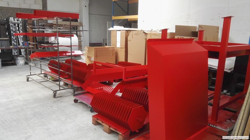 Rote Metallgehäuse und Bauteile auf Paletten und Transportgestellen.