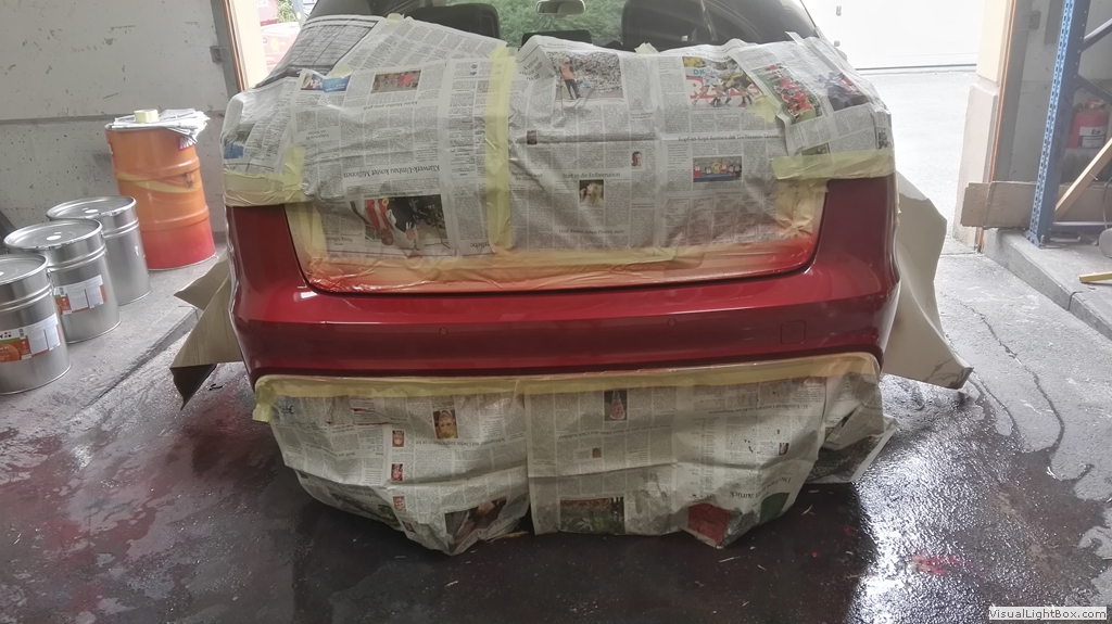 Rotes Fahrzeugteil mit großflächiger Abklebung aus Zeitungspapier.