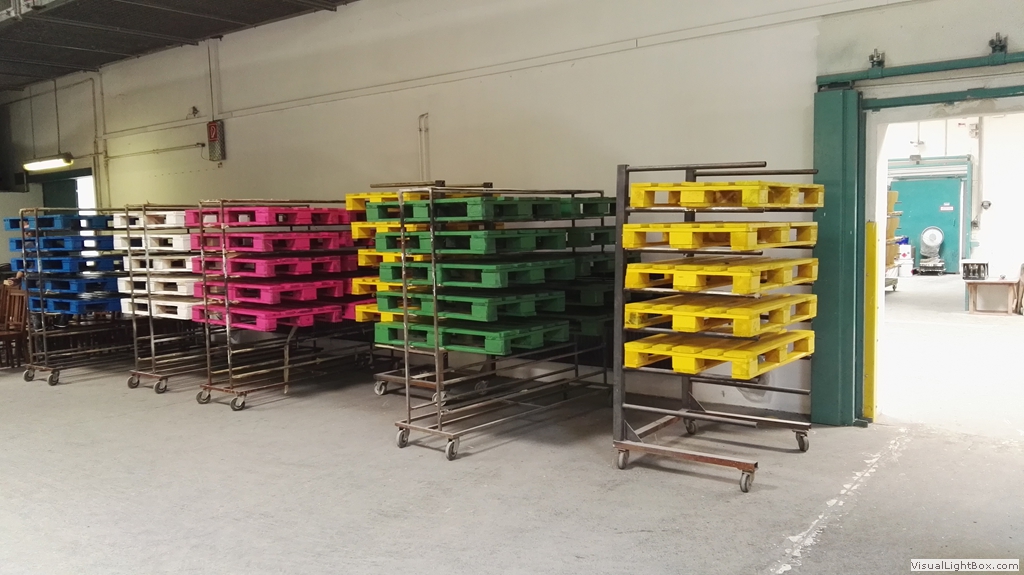 Kleine Paletten in Blau, Weiß, Pink, Grün und Gelb auf Transportgestellen.