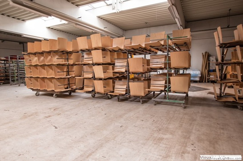 Gebogene helle Holzbauteile auf mehreren Transportgestellen.