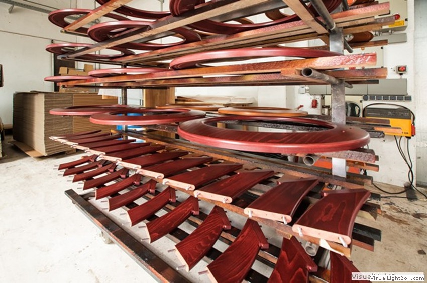 Rötlich braune gebogene Holzbauteile und profilierte Leisten auf einem Ablagegestell.