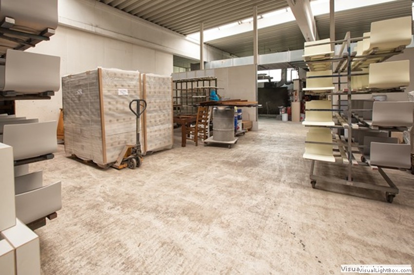 Verpackte Paletten, ein Hubwagen und Ablagegestelle in einem hellen Hallenbereich.