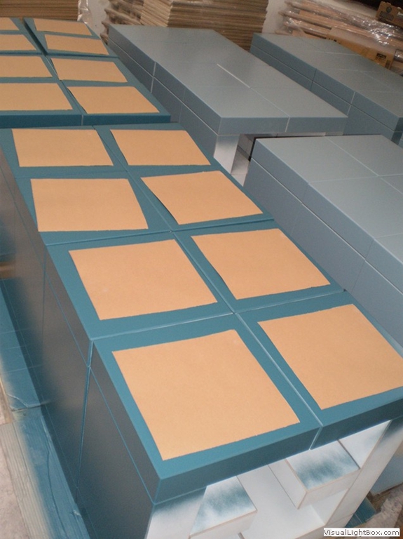 Türkisfarbene Rahmenbauteile mit abgeklebten rechteckigen Flächen.