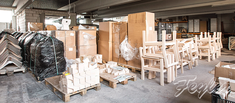 Lagerhalle mit verpackten Paletten, hellen Stuhlgestellen und gestapelten Möbelteilen.